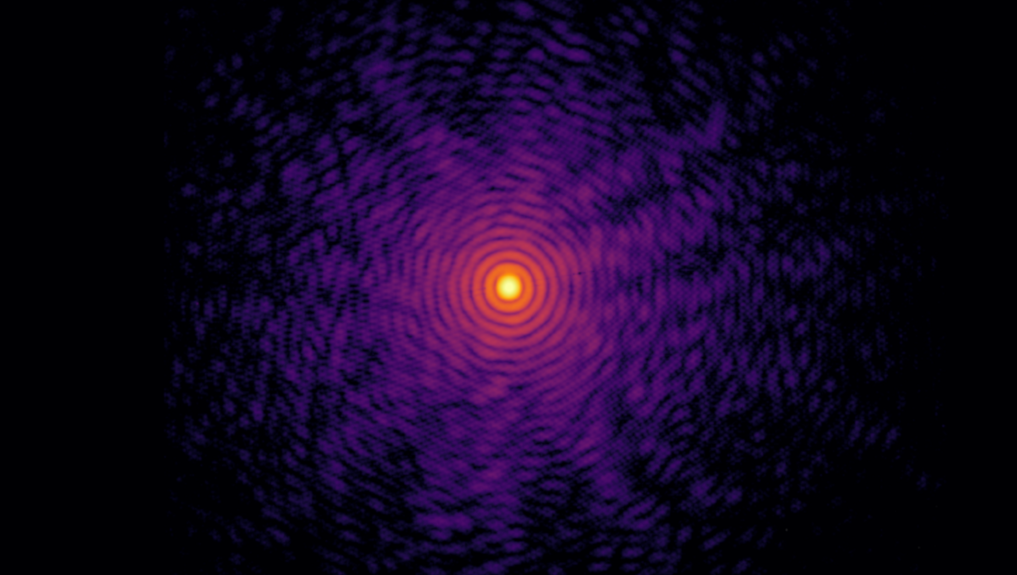 False-color coherent X-ray diffraction pattern collected during an insulator to metal phase transition. The concentric rings and interference pattern reveal changes in the crystal structure.